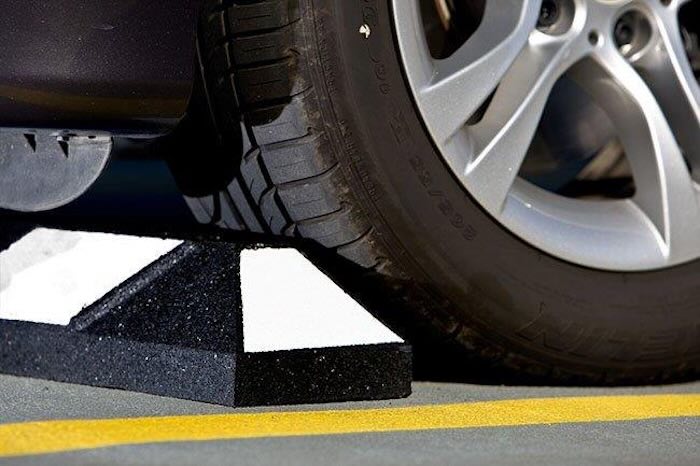 Car next to black and white wheel stop Car next to black and white wheel stop